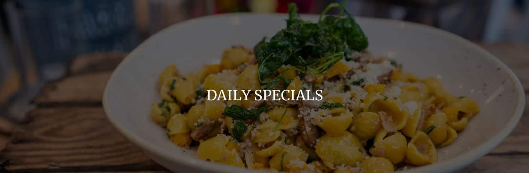 Plate of pasta with cheese and greens on a rustic wooden table, overlaid with 'Daily Specials' text.